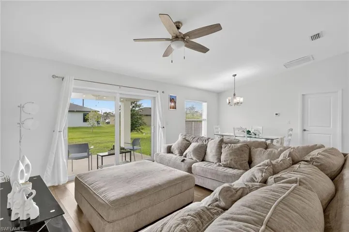 Living area with lofted ceiling, a chandelier, ceiling fan, and light wood finished floors