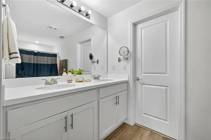 Bathroom with double vanity, wood finished floors, and curtained shower