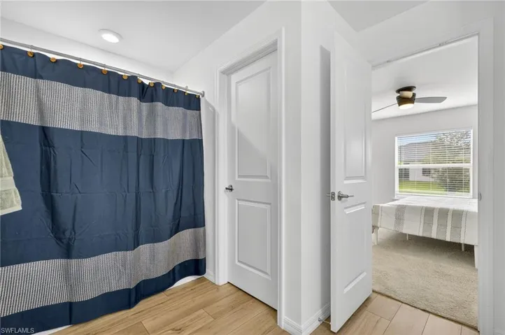 Full bath featuring wood finished floors, ceiling fan, and a shower with curtain