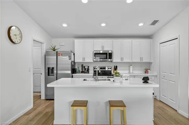 Kitchen with appliances with stainless steel finishes, white cabinets, light wood-style flooring, light countertops, and recessed lighting
