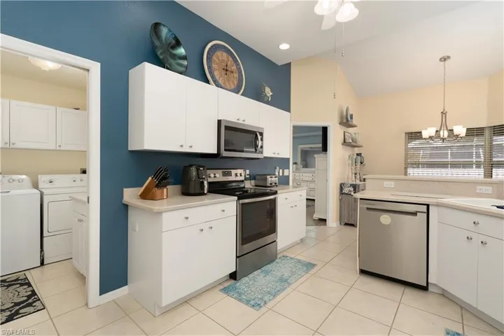 Kitchen with appliances with stainless steel finishes, separate washer and dryer, light countertops, light tile patterned floors, and high vaulted ceiling