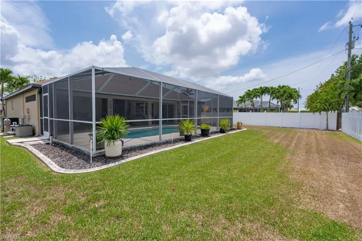 Rear view of property featuring an outdoor pool, a lanai, and central AC unit