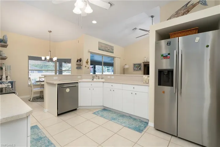 Kitchen featuring appliances with stainless steel finishes, ceiling fan, light countertops, white cabinetry, and lofted ceiling