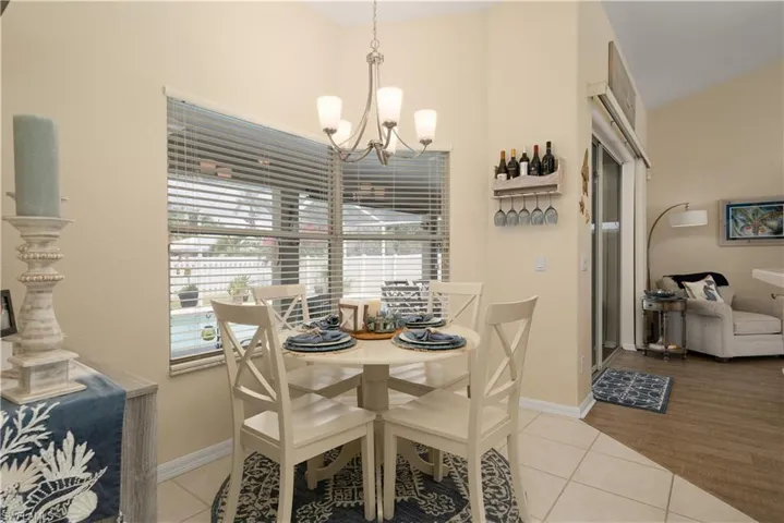 Tiled dining room featuring a chandelier, baseboards, and a high ceiling