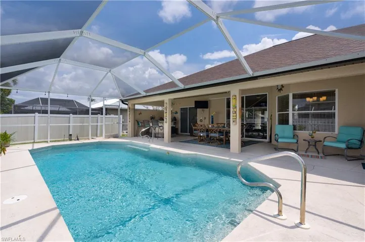 View of pool with a patio, fence, outdoor dining area, and glass enclosure