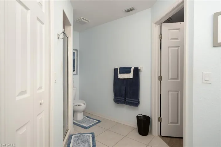 Bathroom featuring toilet, tile patterned floors, a stall shower, and baseboards