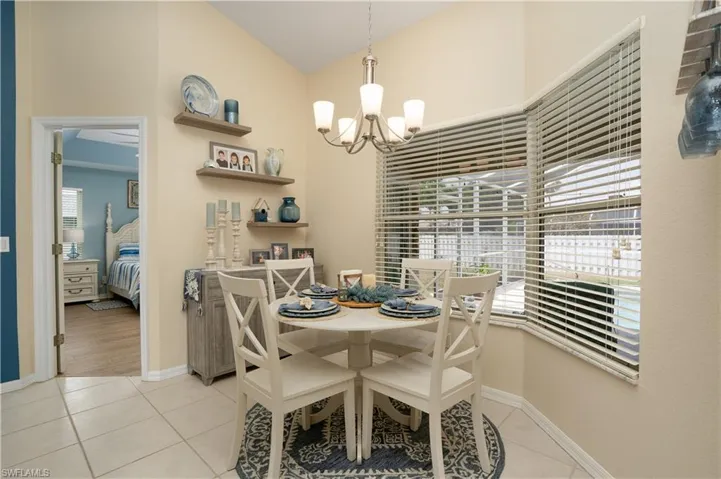 Dining area with a chandelier, light tile patterned floors, baseboards, and vaulted ceiling