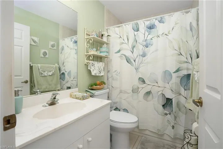 Bathroom with toilet, vanity, curtained shower, and tile patterned floors