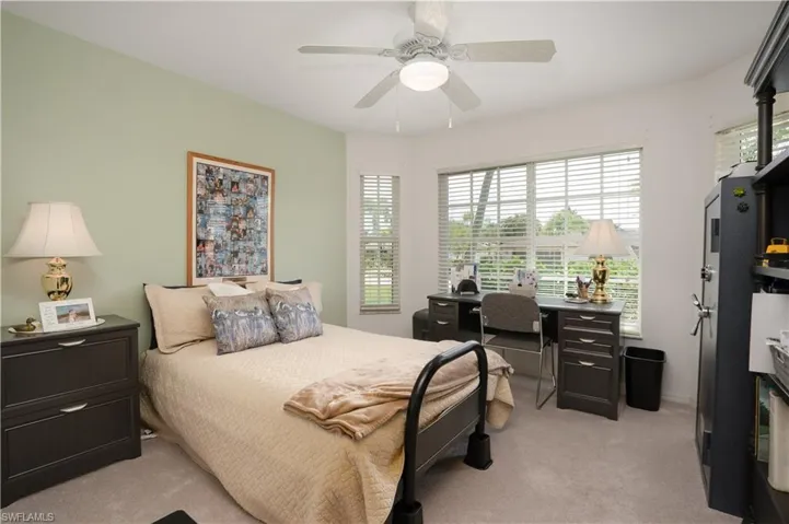 Bedroom featuring light carpet, an office area, and a ceiling fan