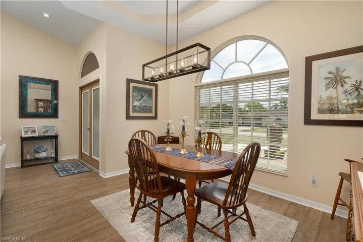 Dining space featuring healthy amount of natural light, baseboards, a high ceiling, and wood finished floors