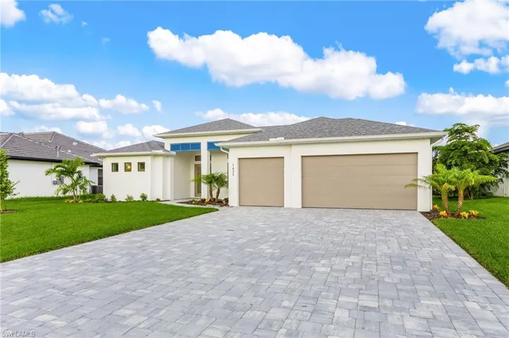 Prairie-style house featuring a front lawn, stucco siding, decorative driveway, and an attached garage