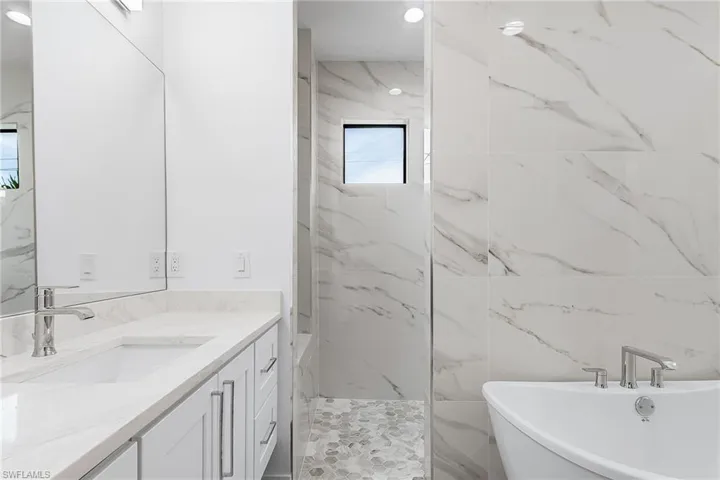 Full bathroom featuring vanity, a freestanding bath, and a marble finish shower