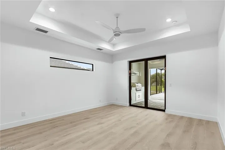 Unfurnished Master Bedroom featuring a tray ceiling, light wood-style floors, a ceiling fan, and recessed lighting