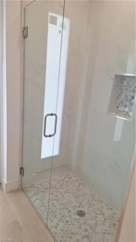 Pool Bathroom tiled shower stall and wood finished floors