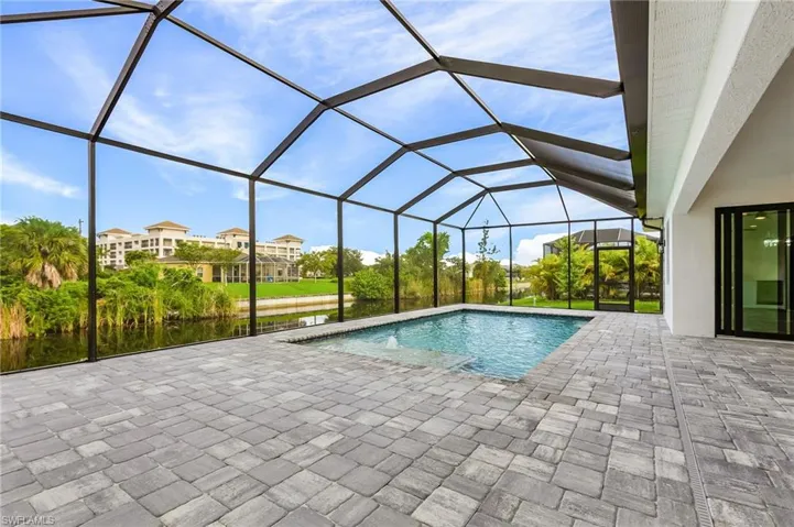 Outdoor pool featuring a sunroom, a lanai, a patio area, and a water view