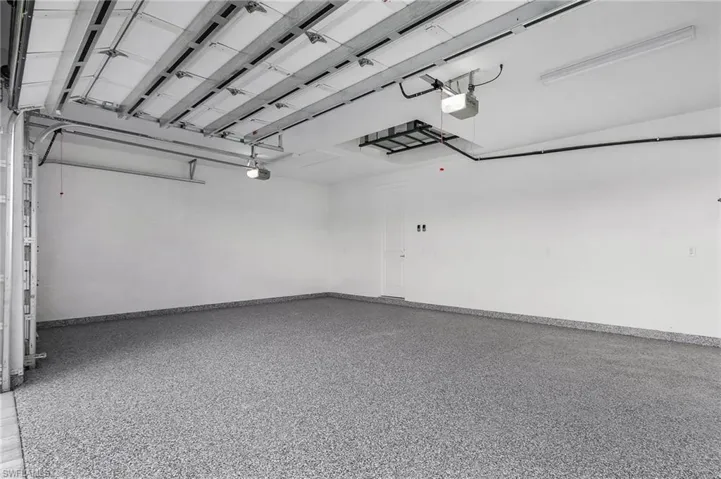 Garage featuring fully epoxied floor and baseboards and two garage doors in a three car garage with two automatic door openers.