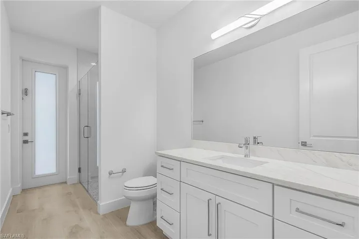 Bathroom featuring vanity, light wood finished floors, and a shower stall