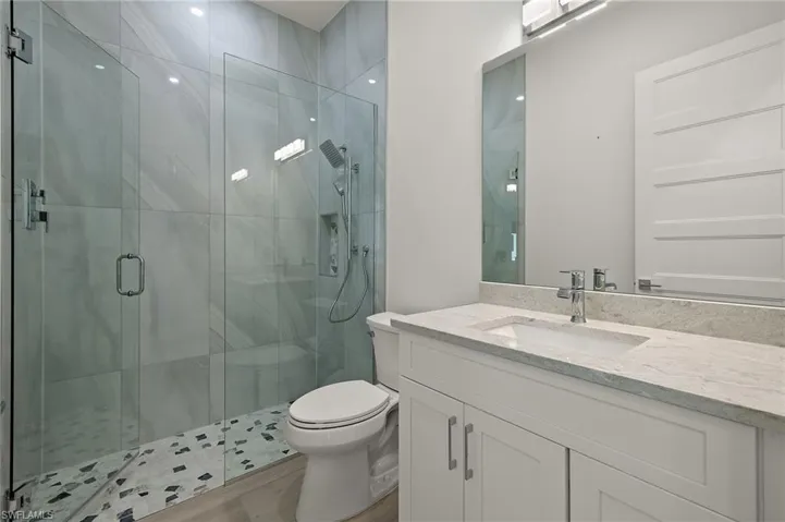 Guest Bathroom with vanity, toilet, walk in shower, and hardwood / wood-style floors