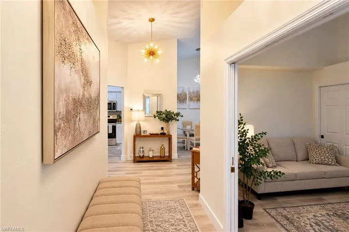 Vaulted ceilings with a modern chandelier, wood-finish flooring, and white trim