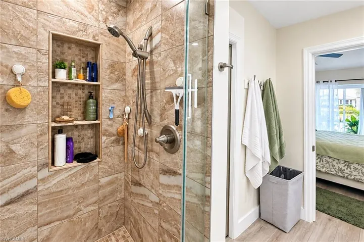 Glass-enclosed shower with stone-look tile surround and mosaic tile flooring