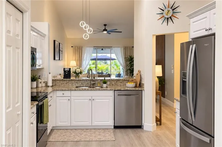 Contemporary kitchen with white cabinetry, stainless steel appliances, granite countertops, and wood-finish flooring