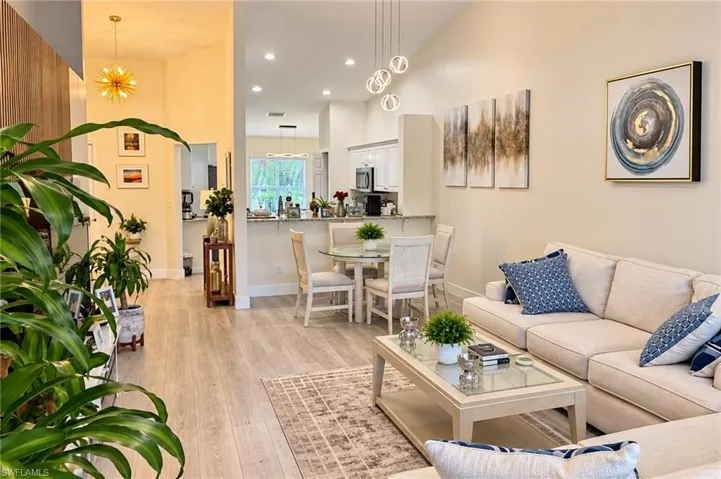 Vaulted ceilings, recessed lighting, wood-finish flooring, and a kitchen pass-through with a breakfast bar