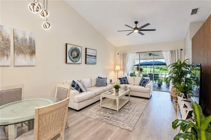 Vaulted ceiling with an integrated ceiling fan, wood-finish flooring, and a sliding glass door providing access to an outdoor area