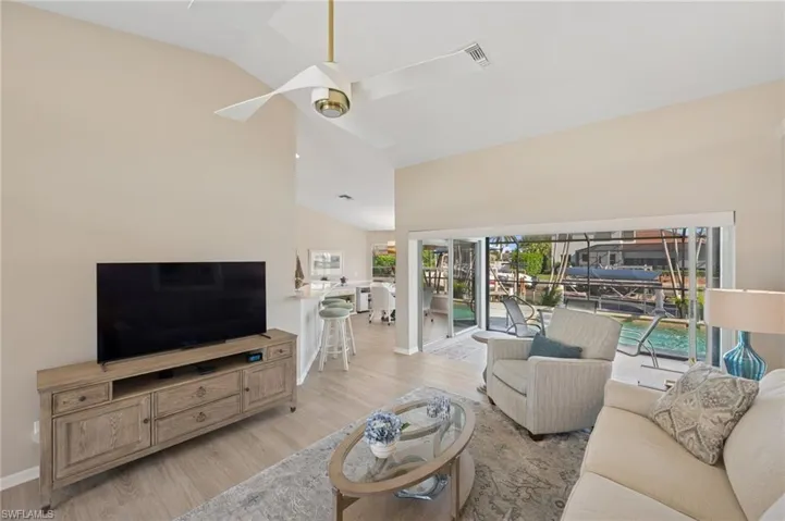 Living area with high vaulted ceiling, light wood-style flooring, baseboards, and a ceiling fan