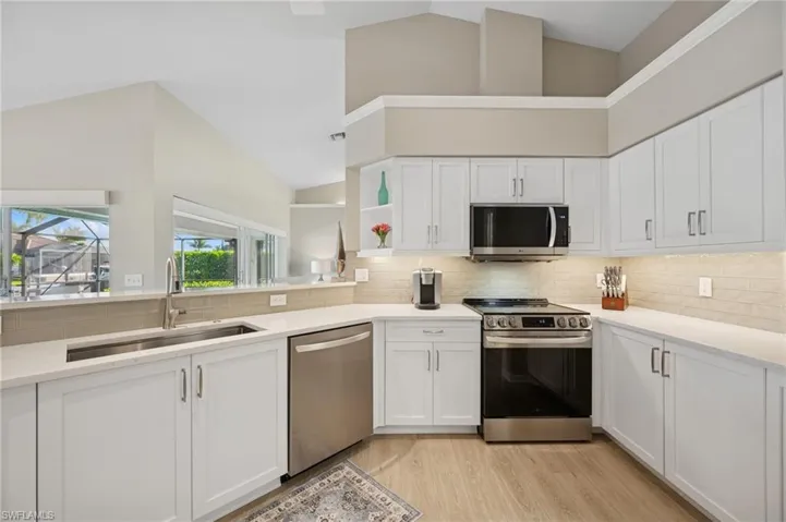 Kitchen with a sink, white cabinets, appliances with stainless steel finishes, and light wood-style floors