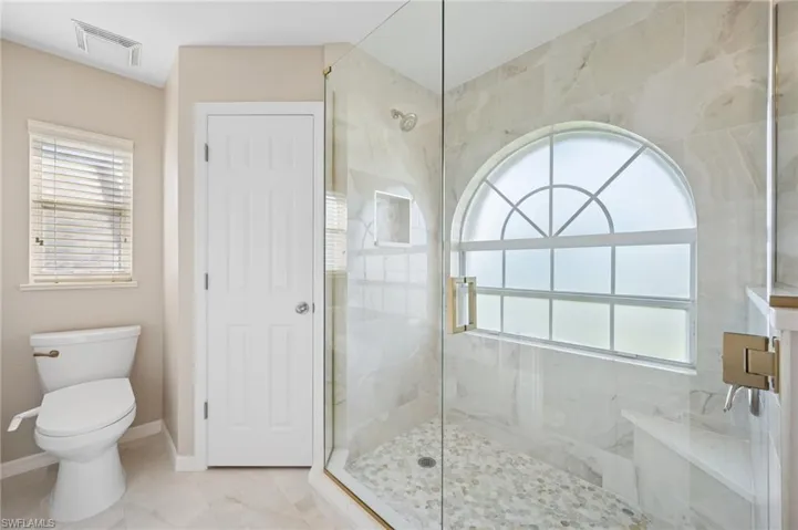 Full bathroom with a shower stall, a healthy amount of sunlight, baseboards, and visible vents