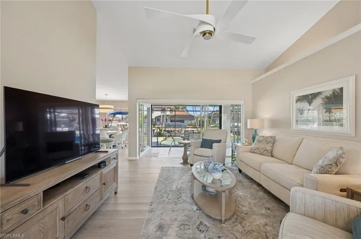 Living room featuring light wood-style floors, high vaulted ceiling, and ceiling fan