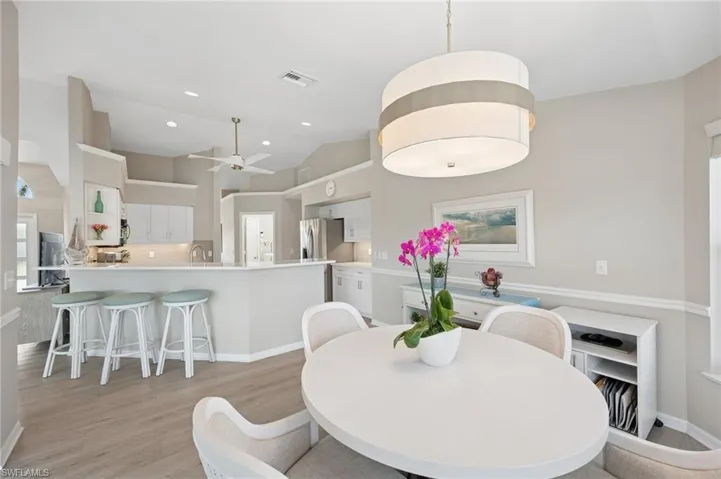 Dining space featuring visible vents, baseboards, ceiling fan, vaulted ceiling, and light wood-style flooring