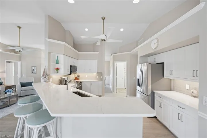 Kitchen featuring a peninsula, a ceiling fan, open shelves, stainless steel appliances, and a sink