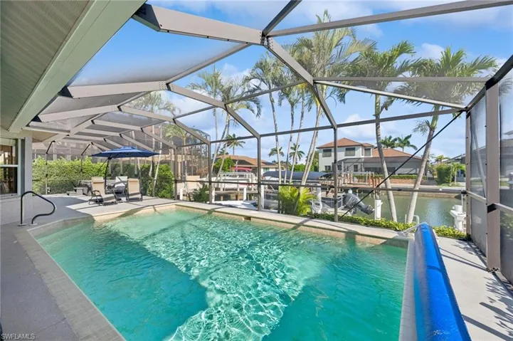 Outdoor pool with a patio, a dock, a water view, and glass enclosure