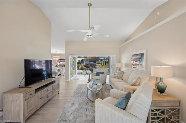 Living room featuring ceiling fan, high vaulted ceiling, and light wood finished floors
