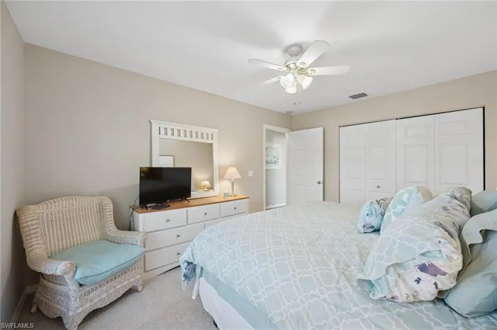 Bedroom with a closet, a ceiling fan, light colored carpet, and visible vents