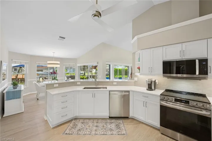 Kitchen with a peninsula, appliances with stainless steel finishes, a sink, and white cabinets