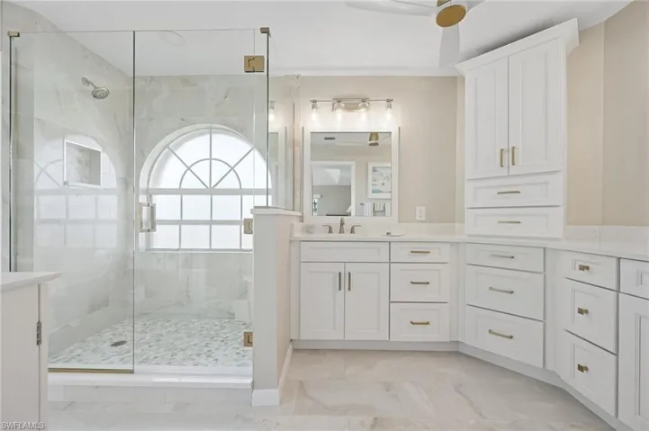 Full bathroom featuring a shower stall, vanity, marble finish floor, and ceiling fan