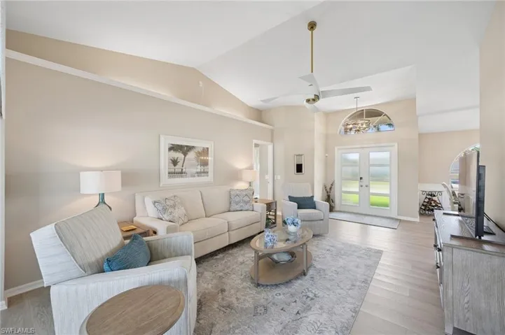 Living room featuring french doors, light wood finished floors, baseboards, and high vaulted ceiling