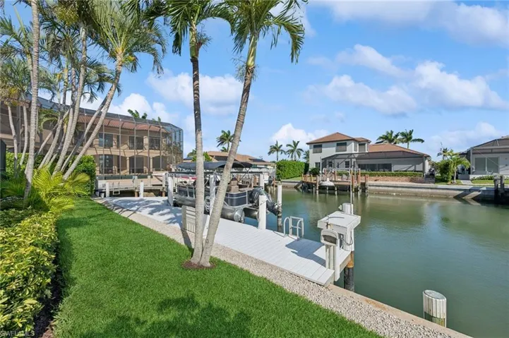 View of dock with a water view, a yard, and boat lift
