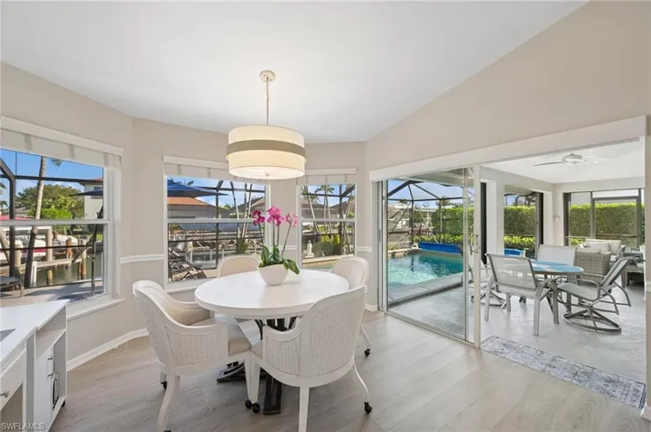 Dining space with a sunroom, a ceiling fan, vaulted ceiling, light wood finished floors, and baseboards