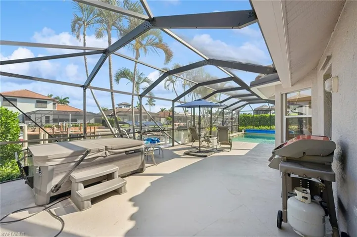 View of patio with an outdoor pool, a grill, glass enclosure, and a hot tub
