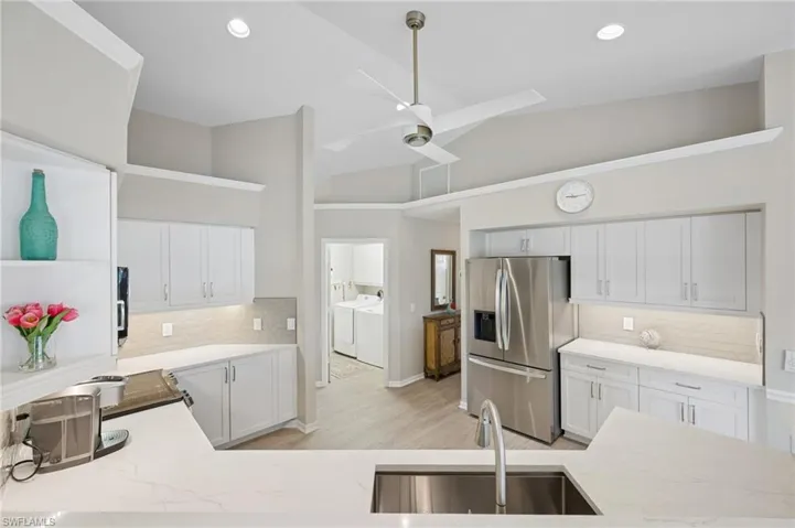 Kitchen with separate washer and dryer, backsplash, stainless steel refrigerator with ice dispenser, high vaulted ceiling, and a sink