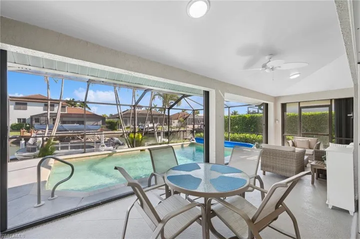 Sunroom / solarium with a water view, a pool, a ceiling fan, and an outdoor hangout area