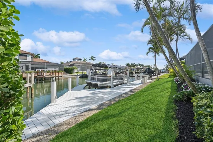 Dock area with a yard, a residential view, a water view, and boat lift