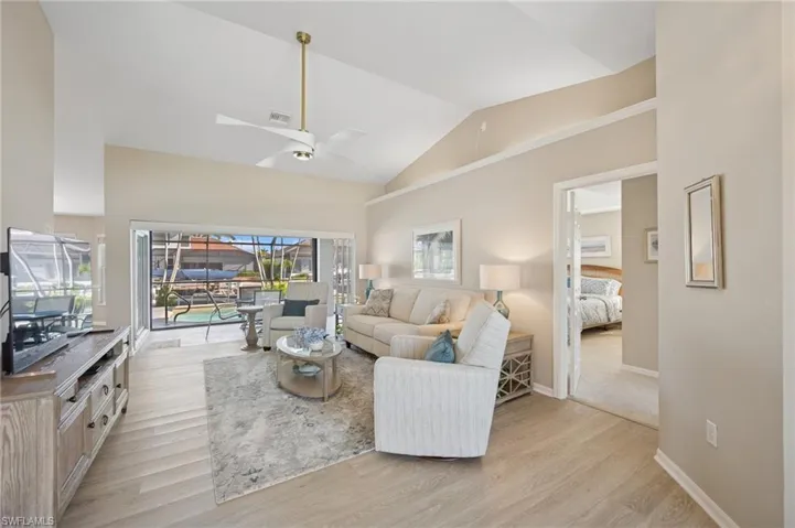 Living area featuring visible vents, baseboards, light wood-type flooring, a ceiling fan, and high vaulted ceiling