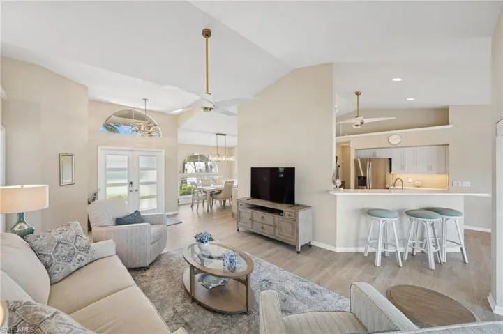 Living room featuring french doors, light wood-style flooring, high vaulted ceiling, and a chandelier