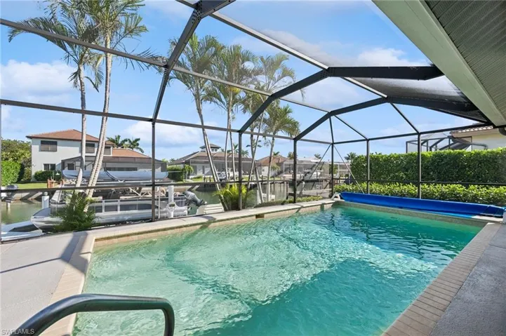 View of pool with a lanai, a dock, a covered pool, and a water view