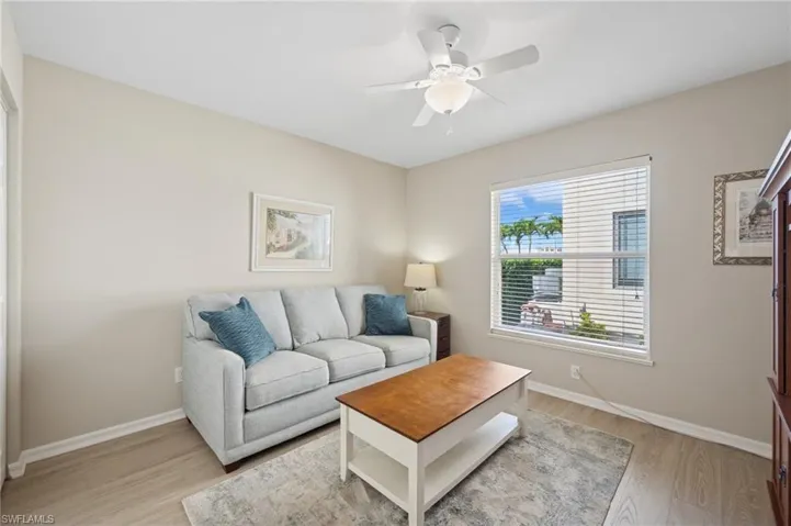 Living area with light wood-style floors, baseboards, and a ceiling fan