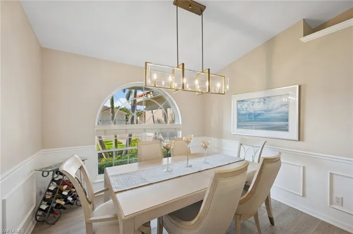 Dining room featuring a chandelier, a decorative wall, wainscoting, and wood finished floors